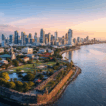 Aerial view of Manila showing the historic Intramuros district, lush greenery, and the modern skyline beside the blue waters of Manila Bay under a bright sky.